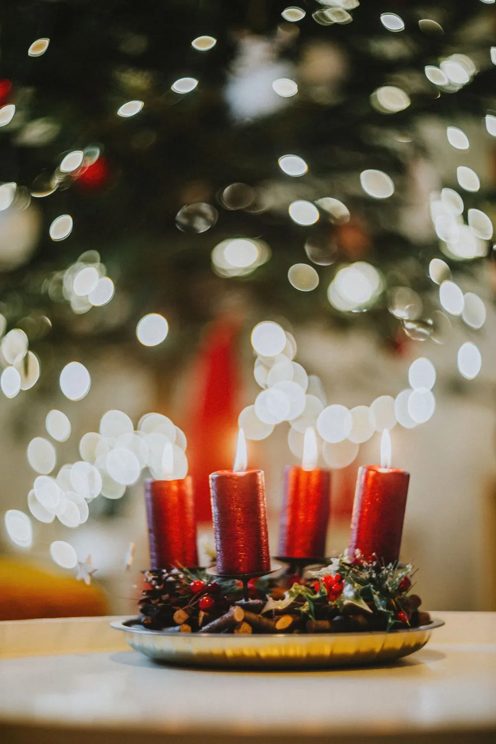 Red candles with festive decorations and Christmas bokeh lights create a warm holiday ambiance.