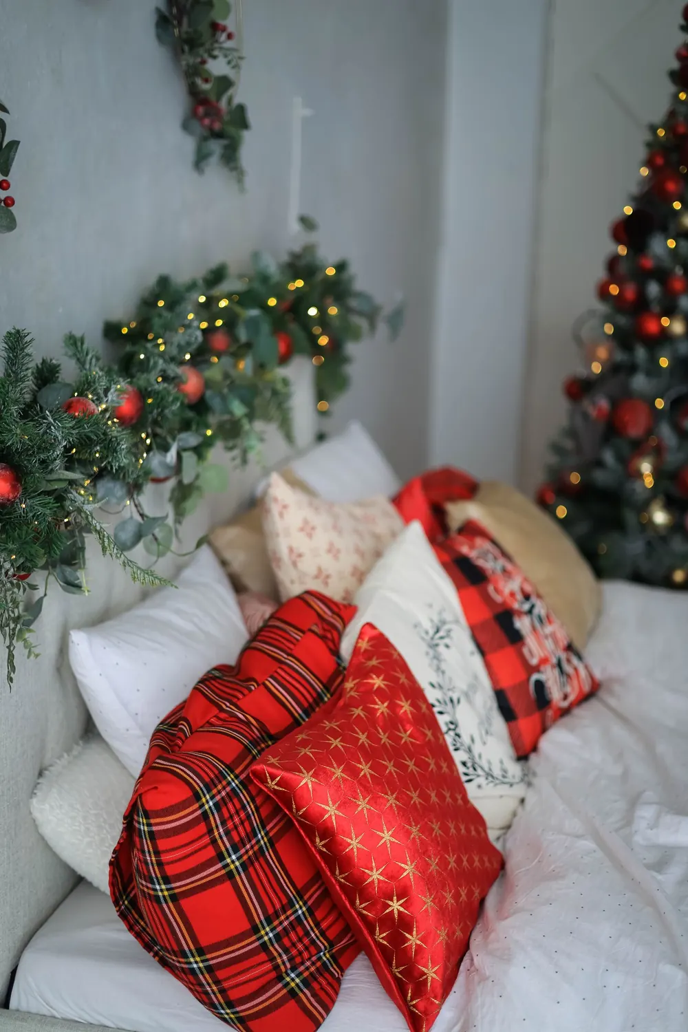 Cozy Christmas-themed bedroom with decorative pillows and festive garlands.