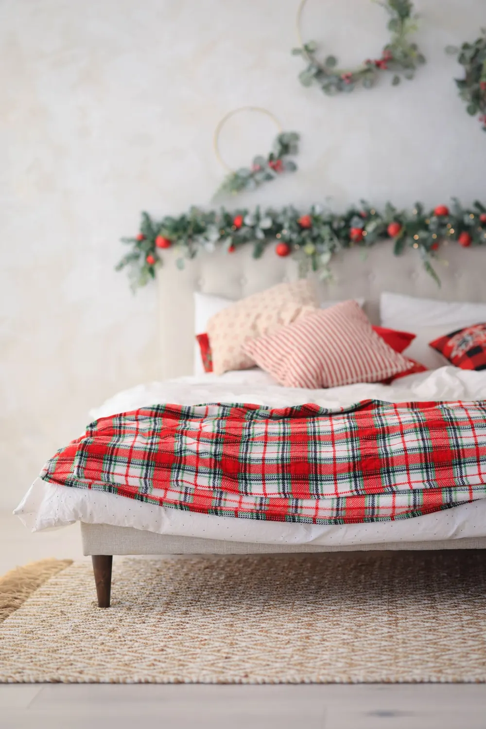 A cozy bedroom featuring festive Christmas decorations and plaid bedding for a warm holiday atmosphere.