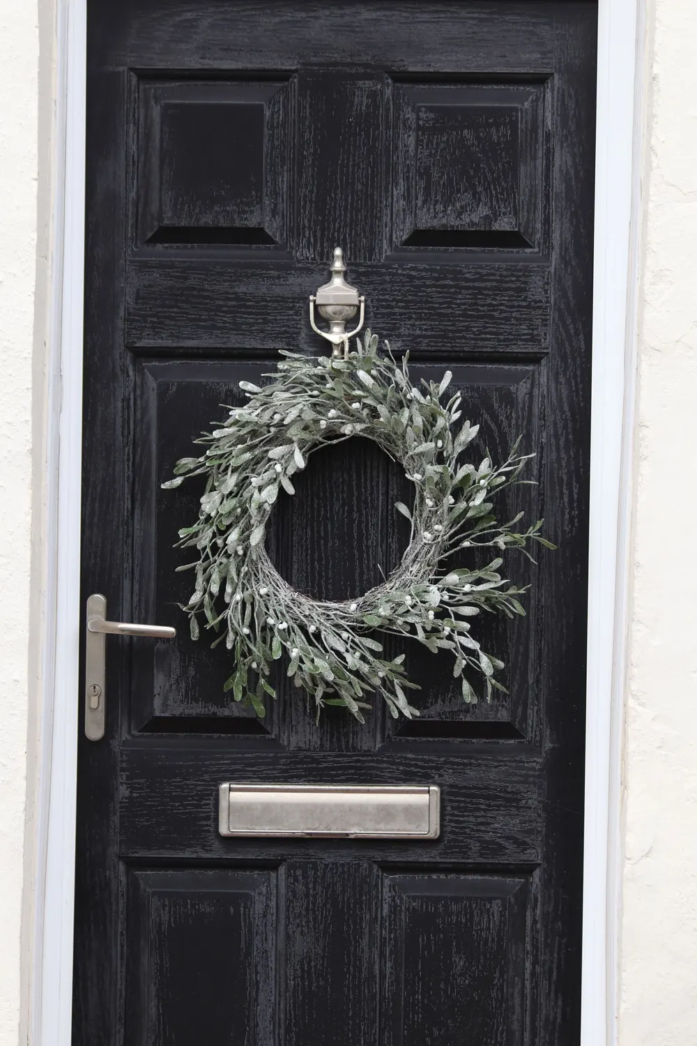 Stylish black wooden door with a winter wreath, creating a festive entrance.