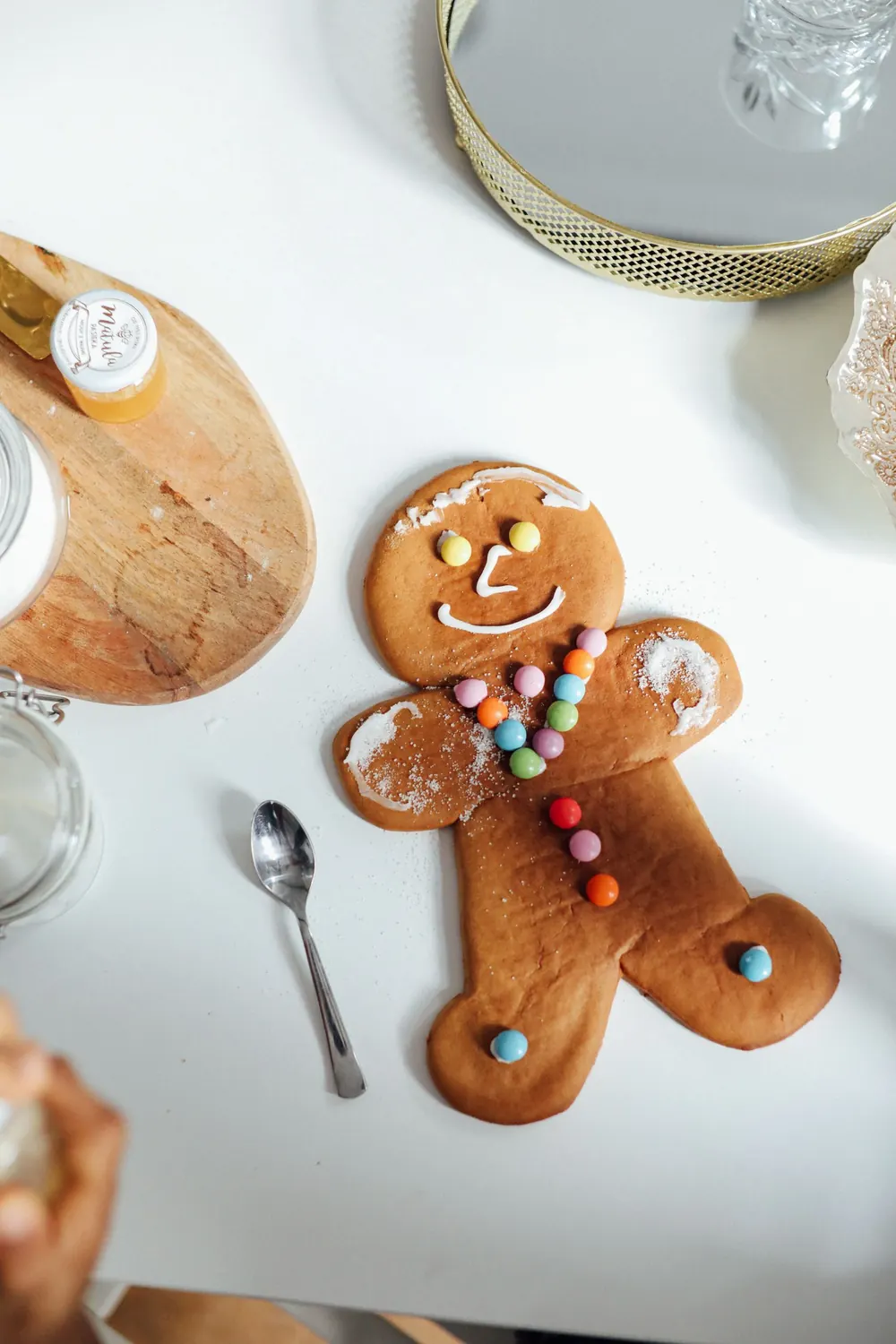 Gingerbread man decorated with colorful candies on a white table, perfect for festive baking themes.