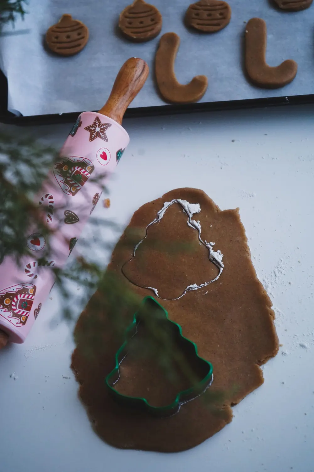 Christmas-themed gingerbread cookies with cutters and rolling pin.