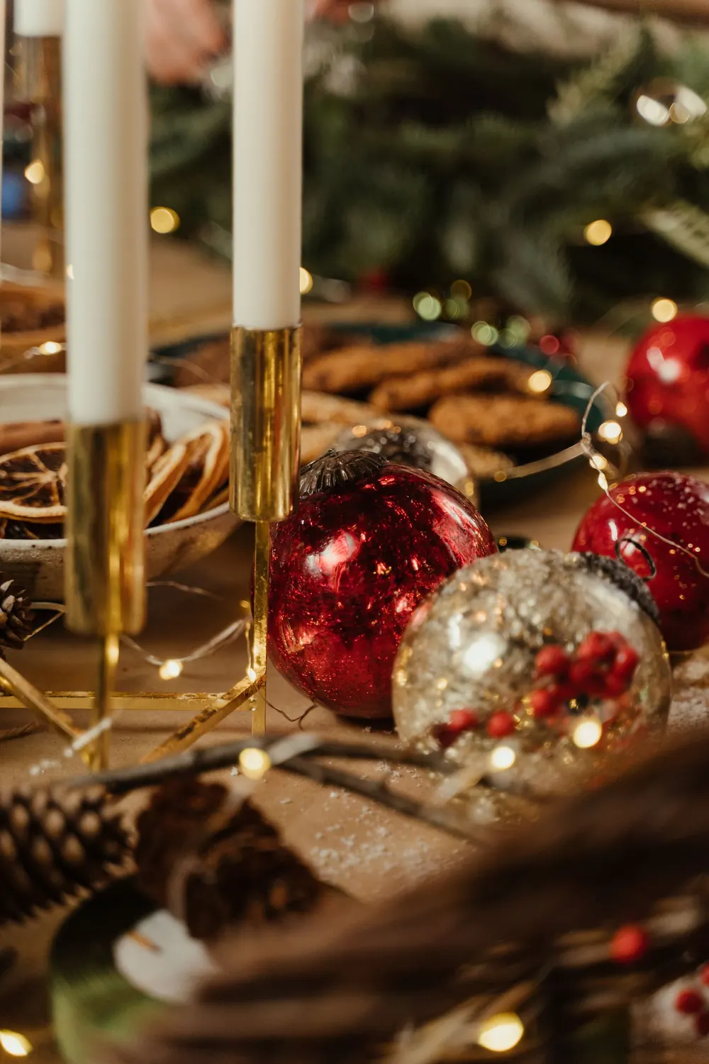 Cozy Christmas setup featuring baubles, candles, and cookies for a festive atmosphere.