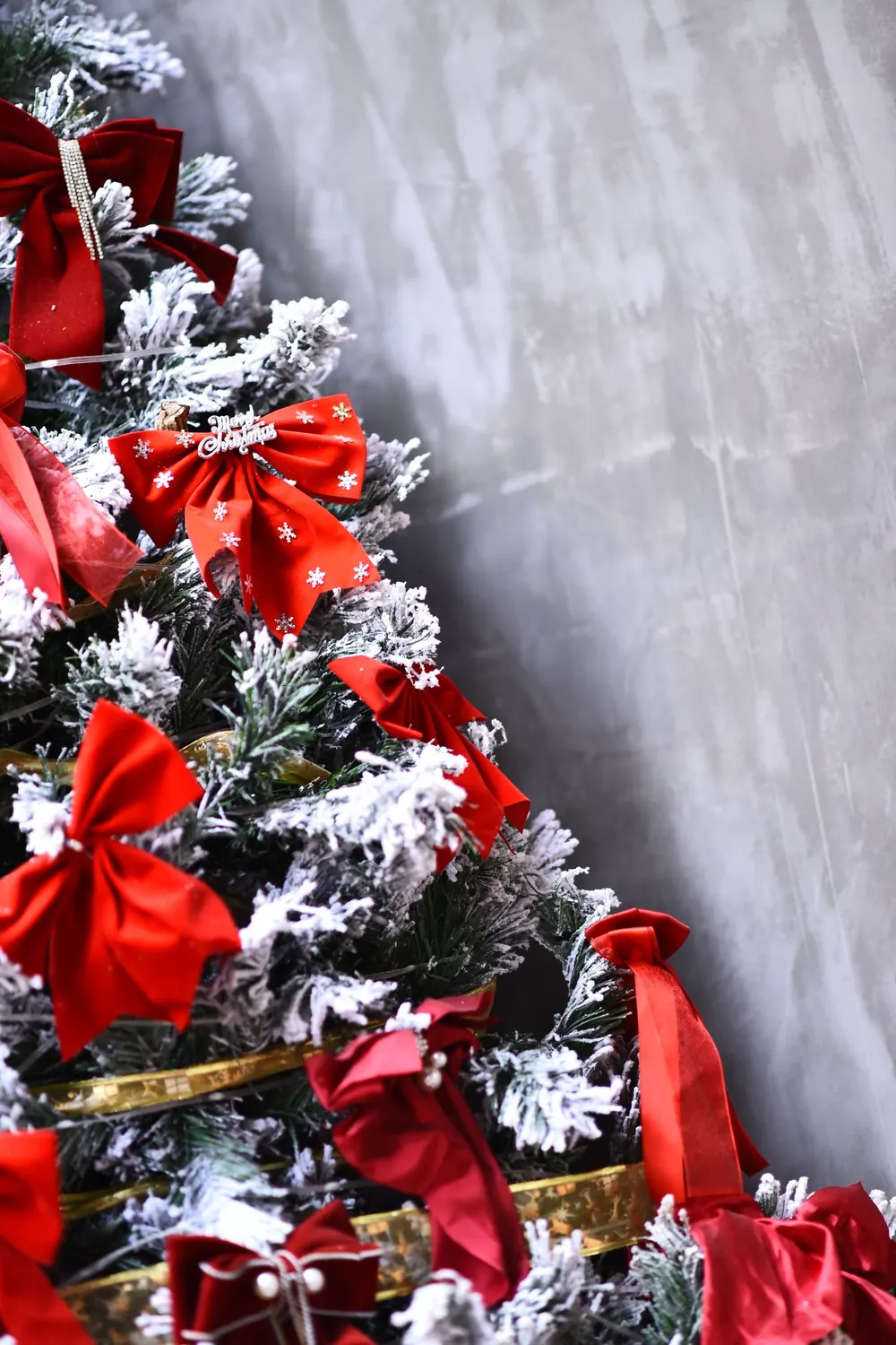 A decorated Christmas tree with red bows and snow-like frosting, perfect for holiday cheer.