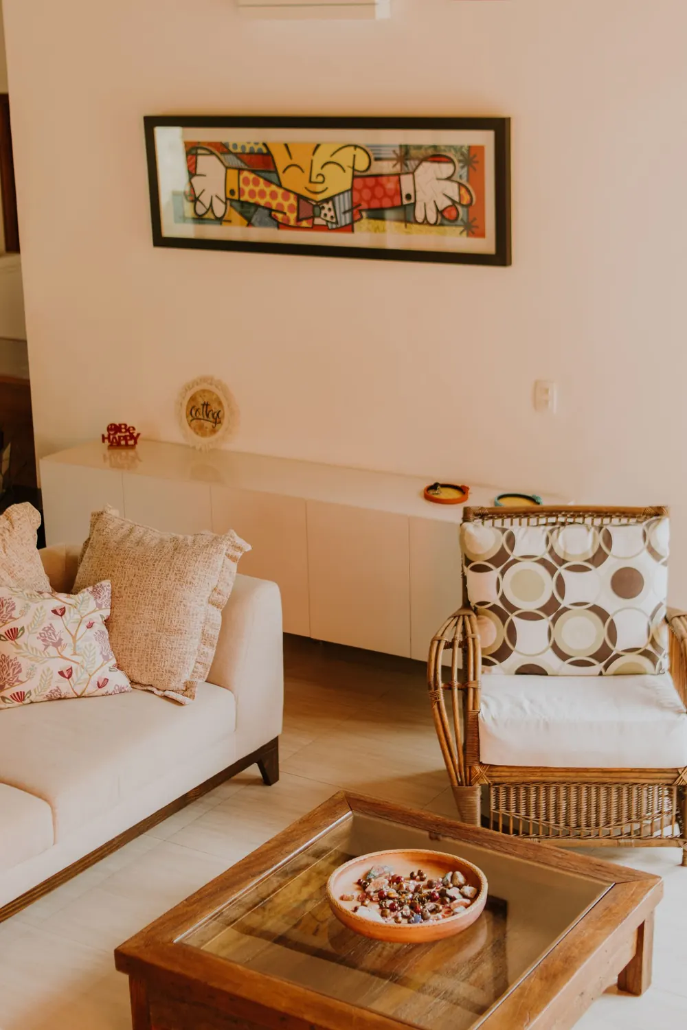 Warm and inviting living room with modern art, rattan chair, and sofa.