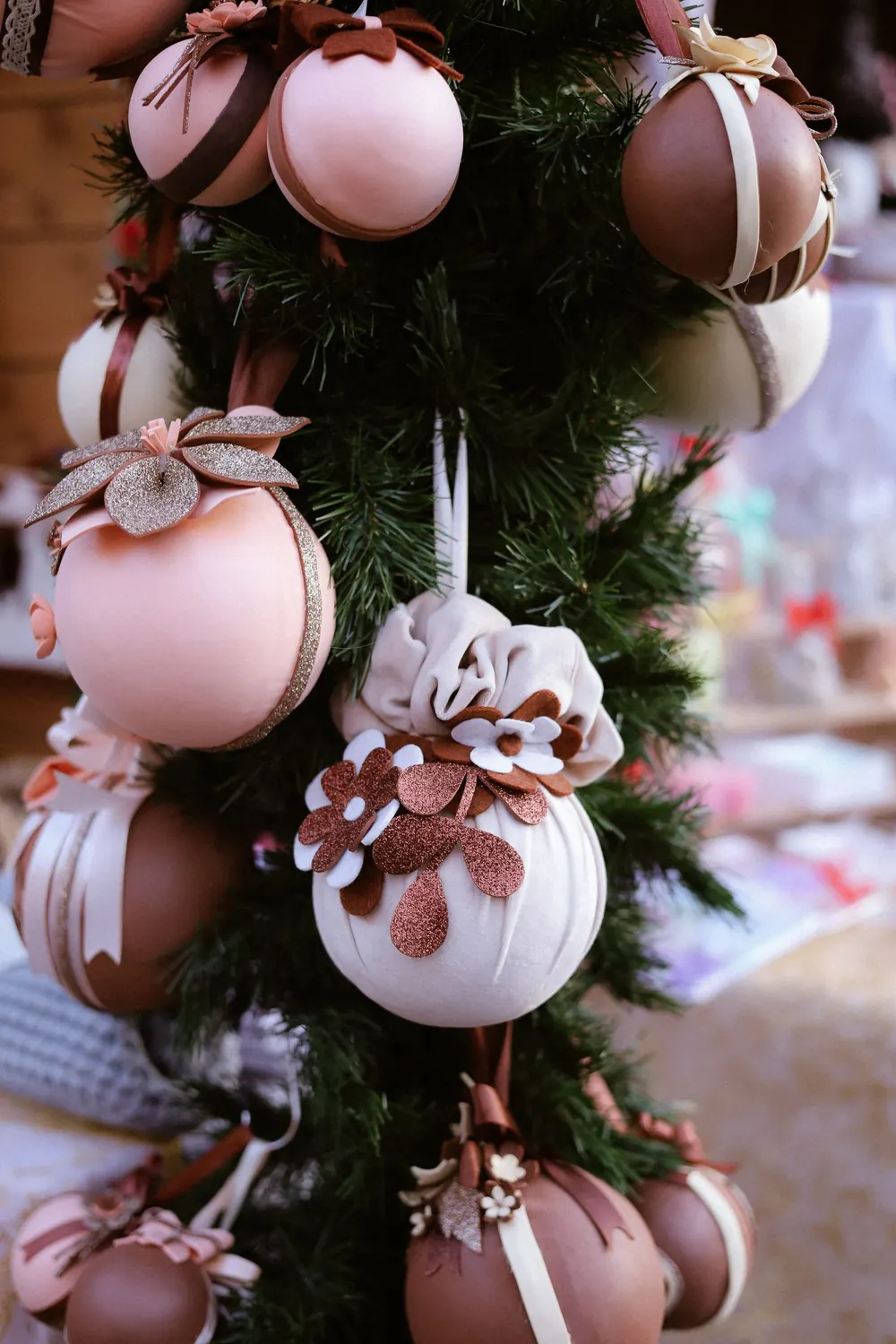Stylish holiday ornaments in cream and rose gold adorn a Christmas tree, creating a festive ambiance.