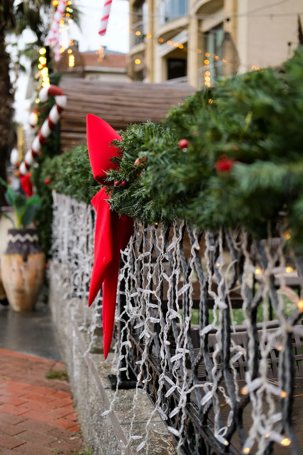 Outdoor Christmas decorations featuring garland, red bows, and lights in a festive setting.