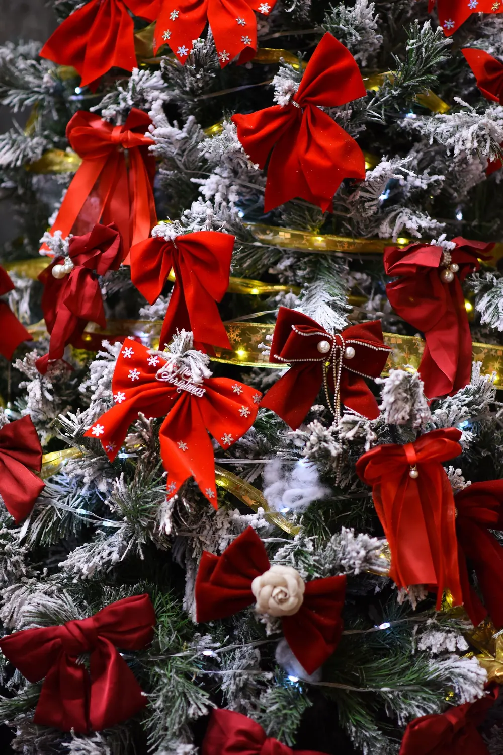 A beautifully decorated Christmas tree adorned with red bows and frosted branches, capturing the festive spirit.