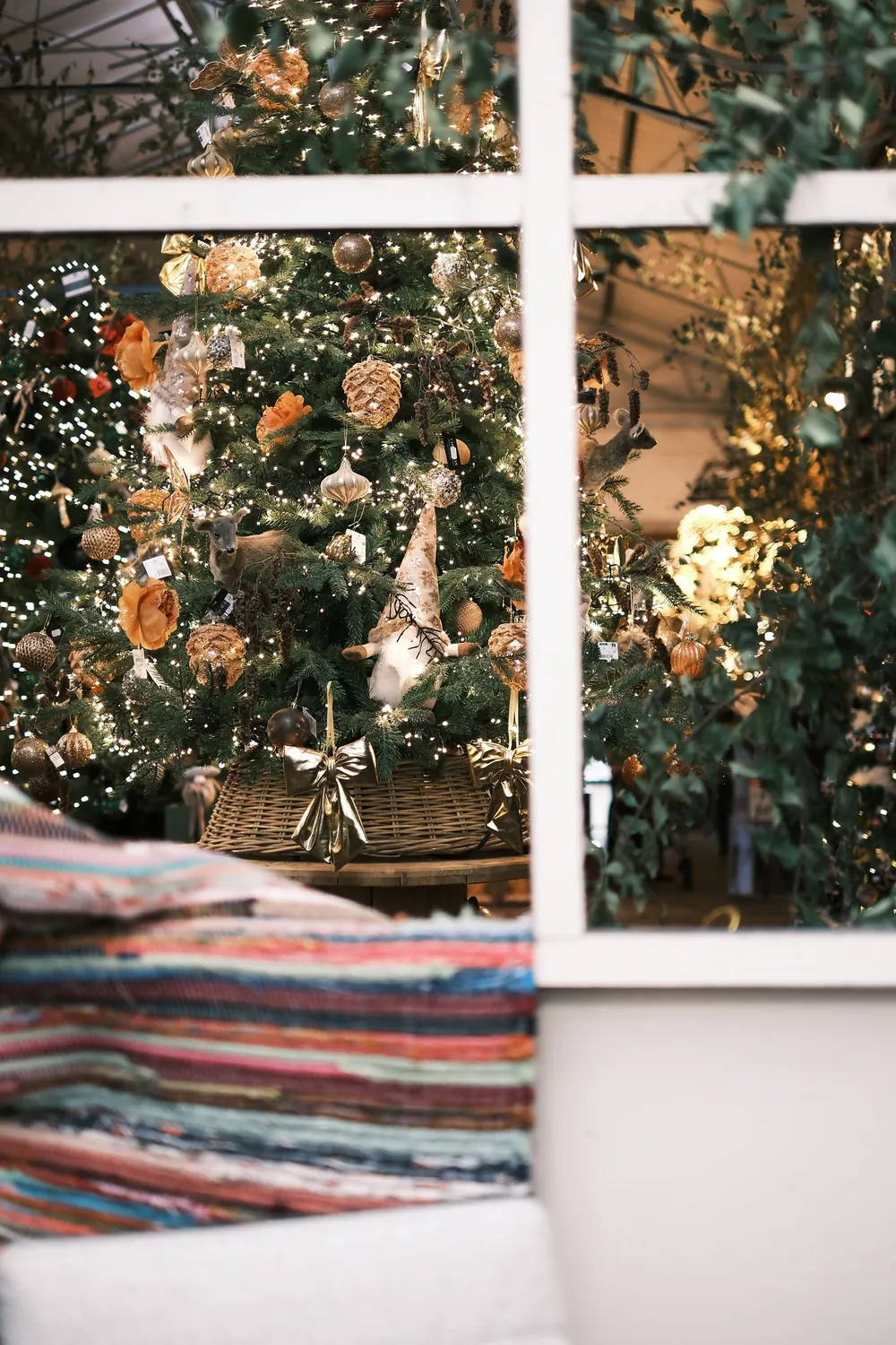 Beautifully decorated Christmas tree viewed through a window, creating a cozy holiday atmosphere.